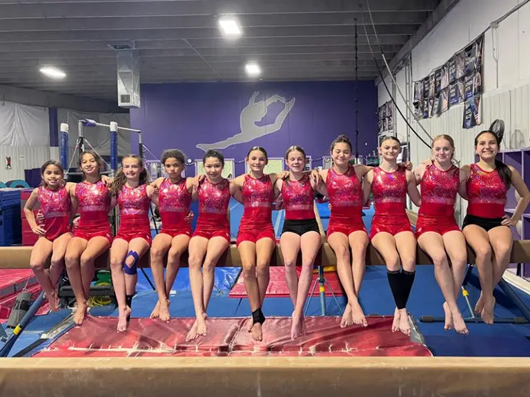 Nga team sitting and smiling on a balance beam